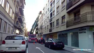 Los bomberos retiran unos cascotes que corrían riesgo de desprendimiento en la calle Primero de Mayo