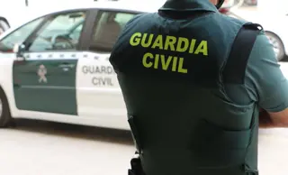 Un agente de la Guardia Civil, de espaldas, junto a un vehículo oficial. GUARDIA CIVIL