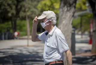 Un hombre con mascarilla y gafas de sol se coloca una gorra durante un "episodio de altas temperaturas". Según la calificación de la Agencia Estatal de Meteorología (AEMET). En Sevilla,(Andalucía
