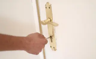 Un hombre introduce una llave en la cerradura de la puerta de una vivienda. EP