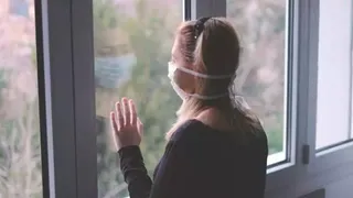 Mujer con mascarilla mira a través de una ventana. Europa Press