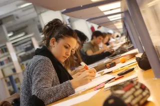Una alumna universitaria, estudiando en una biblioteca.