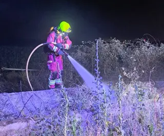Un bombero apagando el incendio generado por el coche en Pelabravo. 