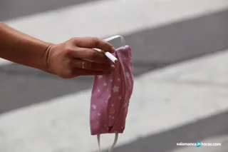 Una mujer sostiene un cigarro y una mascarilla de la mano | FOTO S24H