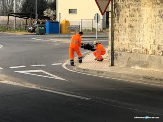 Dos operarios del servicio de carreteras retiran restos de un accidente