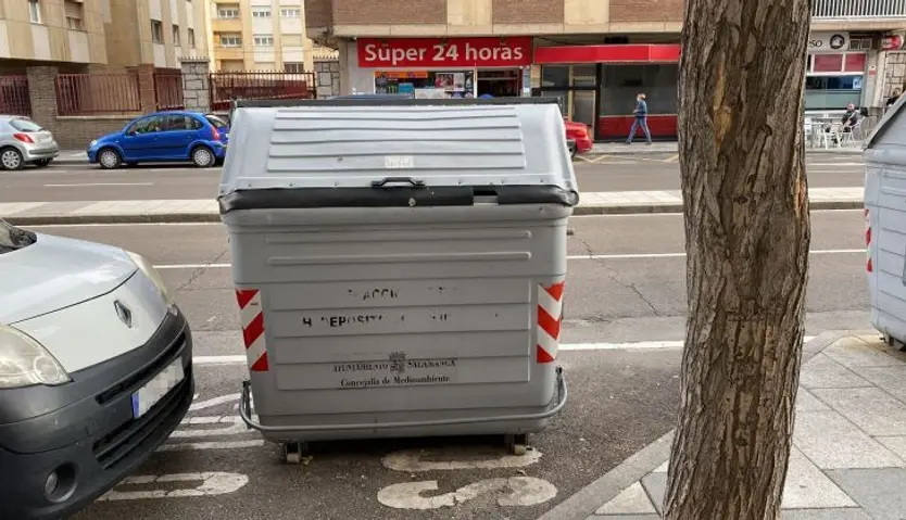 Un contenedor y un vehículo en un estacionamiento reservado para motos