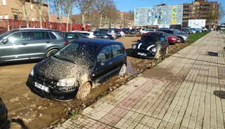 Coche atascado en el barro del parking público de Puente Ladrillo