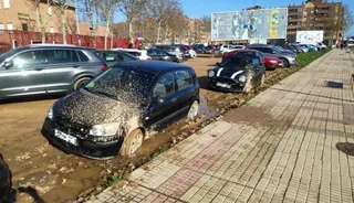 Coche atascado en el barro del parking público de Puente Ladrillo