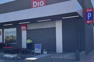 Operarios arreglando la puerta del supermercado que ha sufrido un robo en Peñaranda
