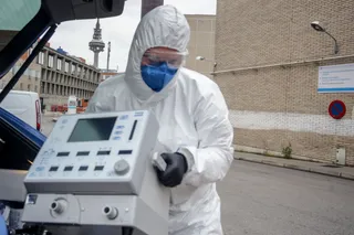 Un técnico protegido con un traje, guantes y mascarilla en el Hospital Gregorio Marañón, saca un respirador del maletero de su coche antes de montarlo en el Hospital, elemento imprescindible para m