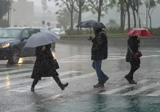 Peatones bajo la lluvia (Imagen de archivo)