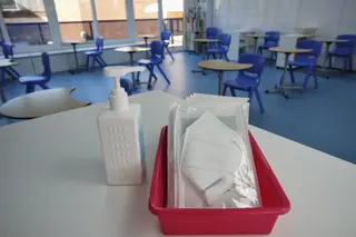 Mascarillas y gel desinfectante en la mesa del profesor de un aula (archivo)