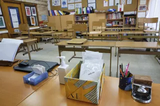 Mascarillas y gel desinfectante en la mesa del profesor de un aula de un colegio