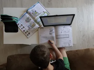 Un alumno de primaria hace los deberes en su hogar con varios libros. Foto de archivo EP