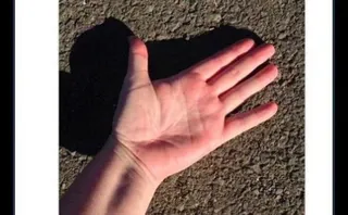 Mano apoyada sobre el asfalto