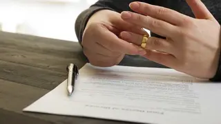 Una persona se retira la alianza tras firmar los papeles del divorcio