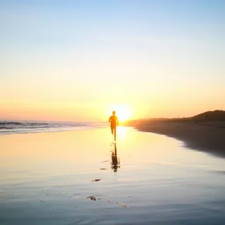 Persona pasea por una playa durante un atardecer