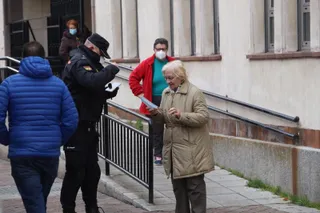 El agente de Policía Nacional entrega la mascarilla a la señora
