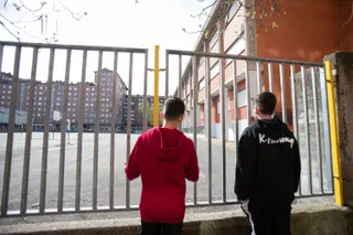 Dos adolescentes observan el patio de un colegio.