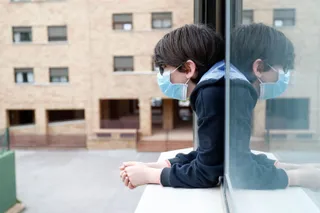 Un niño con una mascarilla se asoma a la ventana de su casa cuando queda tan solo una semana para que niños y preadolescentes puedan salir a la calle durante el confinamiento por el coronavirus, en