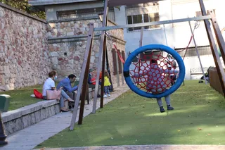 Un niño juega en un parque de la ciudad mientras sus padres esperan sentados. Foto SALAMANCA24HORAS.