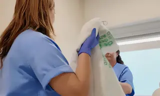 Personal Técnico de Cuidados Auxiliares de Enfermería (TCAE) aseando a un paciente en el Hospital Virgen Macarena. Imagen de archivo