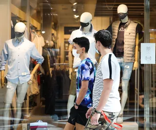 Dos jóvenes pasan junto a una tienda de ropa del Centro Plaza Norte 2, La Cúpula de Madrid, durante el segundo día de la Fase 2 de desescalada, y un día después de reanudar su actividad puesto qu