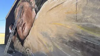 Uno de los artistas rematando su pintura mural en Rágama