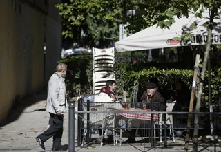 Un hombre camina frente a la terraza de un bar donde hay sentadas otras tres personas en la zona básica de salud de Guzmán el Bueno, en el distrito de Chamberí, en Madrid (España), a 26 de octubre