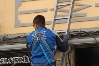 Un trabajador electricista subido a una escalera en las calles de Salamanca