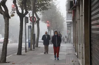 Gente paseando por la mañana de viernes 12 de noviembre por Av de Mirat con niebla y frío en invierno
