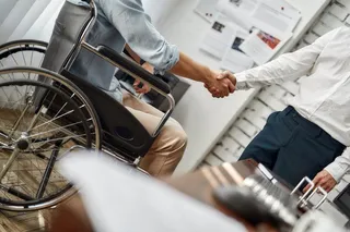 Una persona con discapacidad firmando un contrato de trabajo. Foto EP