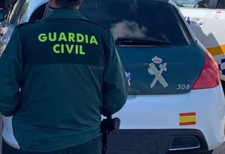 Un agente de la Guardia Civil de espaldas y junto a un vehículo oficial del cuerpo. | FOTO: EP
