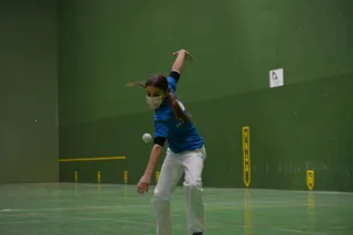 Una joven realiza un saque en Pelota a Mano.