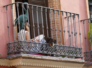 Una joven leyendo un libro en la terraza de su casa durante el estado de alarma. Foto de archivo